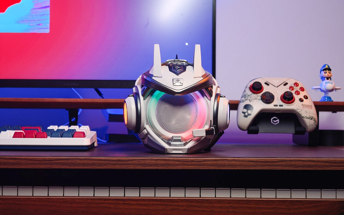 Silver-white OLLIE speaker beside a controller in an RGB-lit desktop setup