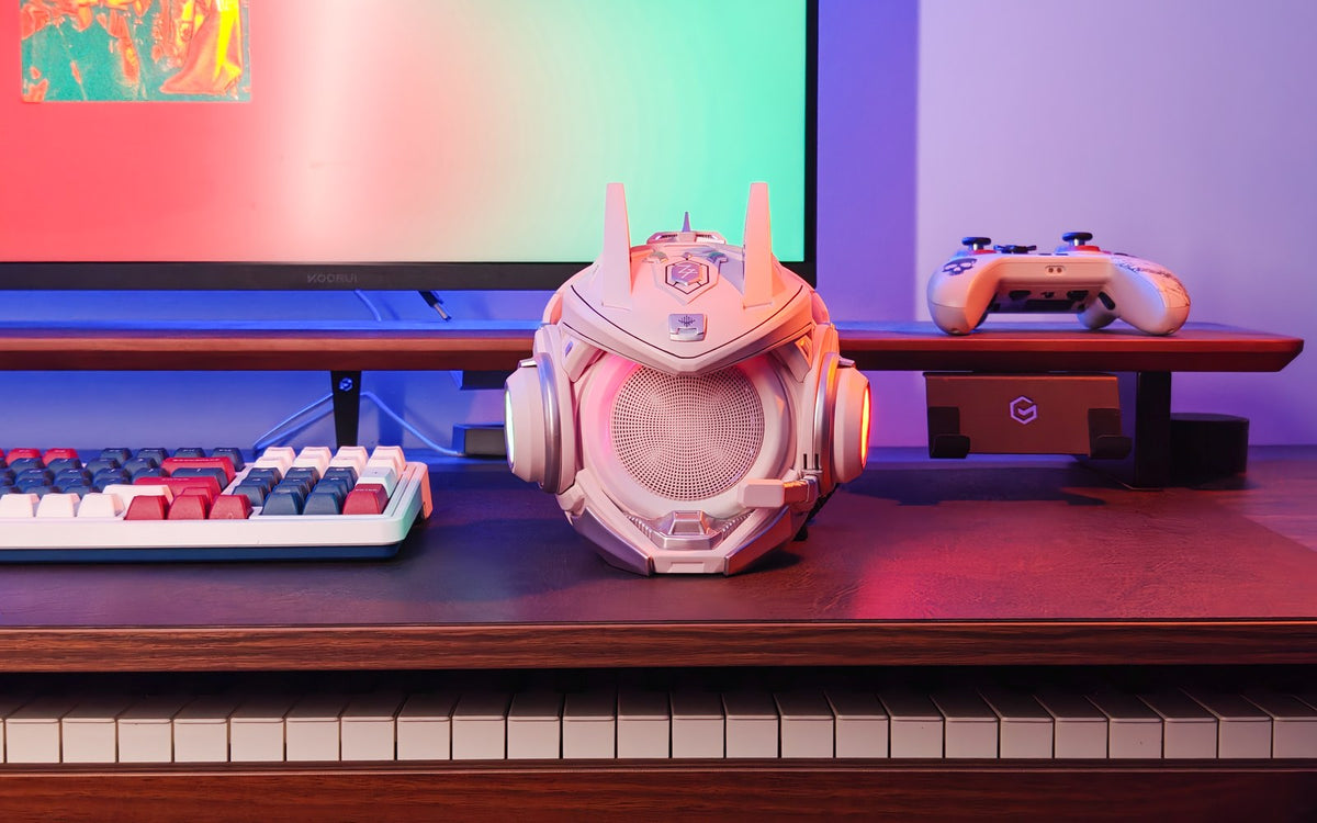 Pink OLLIE speaker in an RGB-lit desktop setup with a keyboard and controller